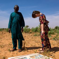 Niamey (Niger), Ceinture Verte. Boubacar Ganda et Ursula Meyer, doctorante à l’Institut de géographie et durabilité. Au sol, le panneau d'un lotissement immobilier, signe du grignotage de cette zone. Photo Maurice Ascani