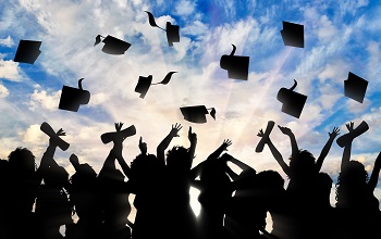 Students graduate cap throwing in sky