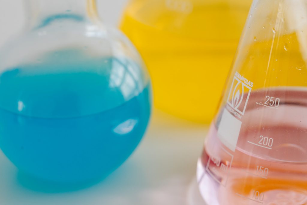 kaboompics close up of colorful laboratory flasks on yellow background 26219