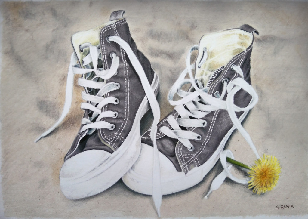 Tennis shoes with a yellow flower beside the right one