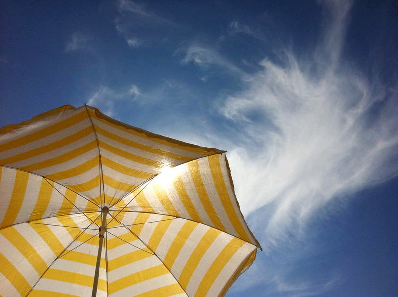 Yellow parasol with the sun beating down on it